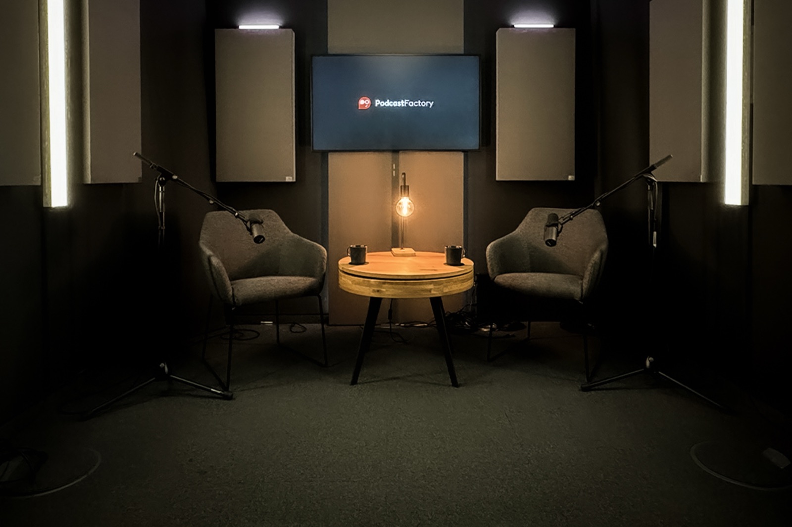 Lounge-Set mit zwei Sesseln, rundem Holztisch und Tischlampe vor einem Bildschirm