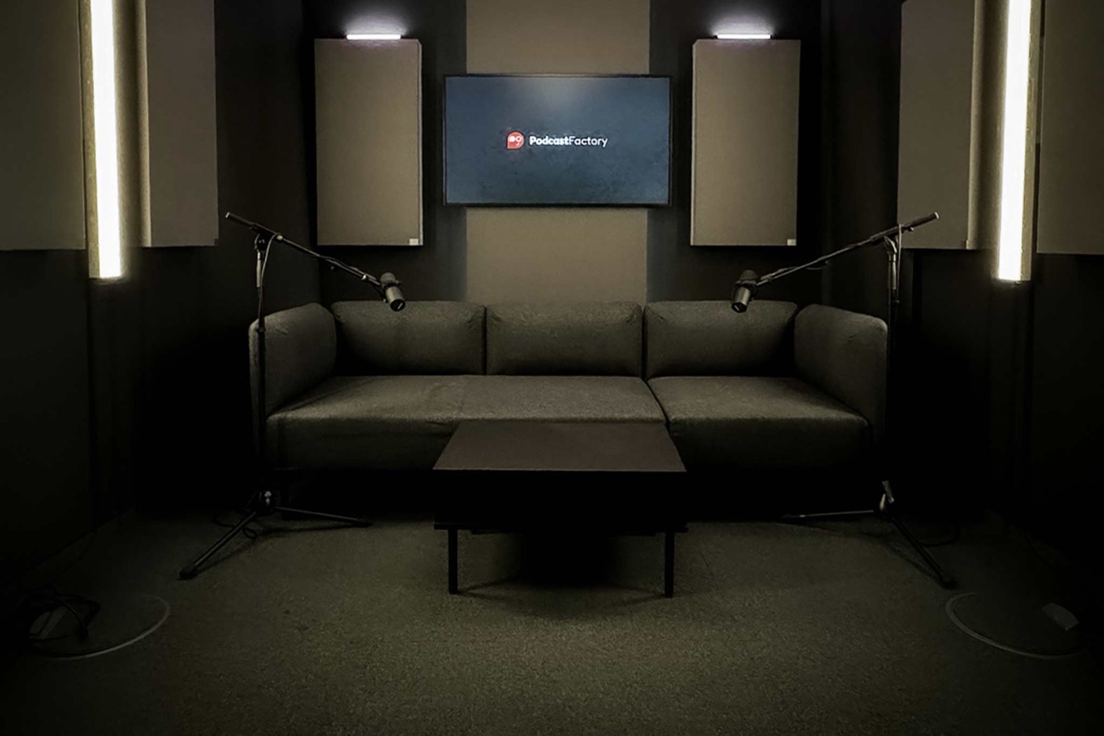 Graues Sofa mit Couchtisch und zwei Galgen-Mikrofonständern im Studio